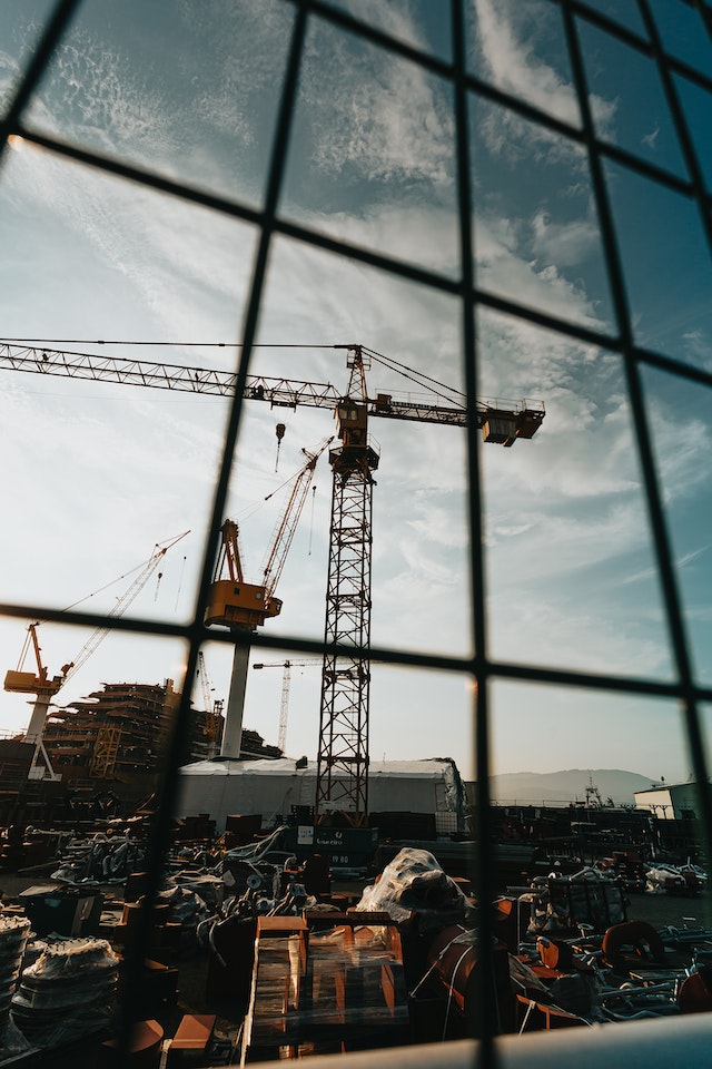 Photograph of a construction site in Islamabad with workers and cranes in the background